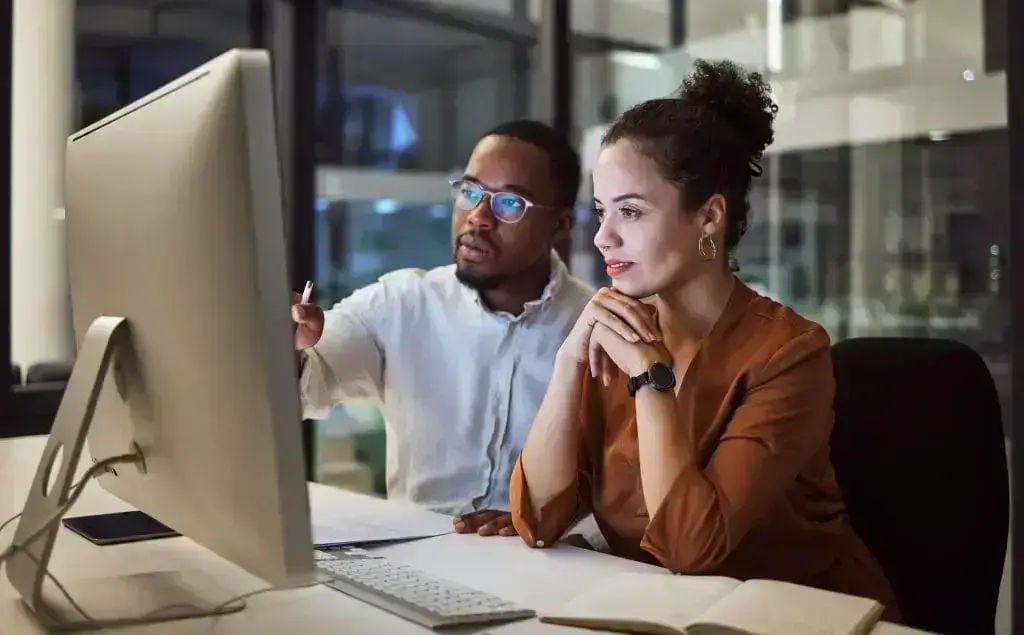 Two logistics professionals reviewing performance data on the Enveyo platform at a desktop workstation